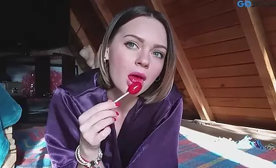 Spreading her legs, girl passionately licks a popsicle